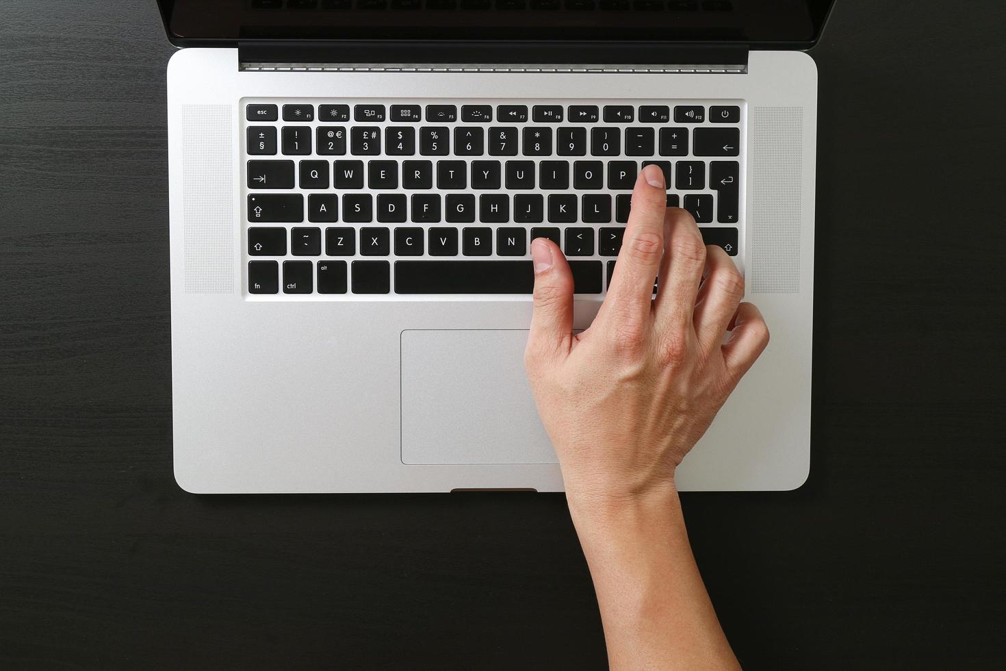 vue de dessus d'un homme d'affaires tapant du clavier avec un ordinateur portable sur un bureau en bois dans un bureau moderne, noir et blanc photo