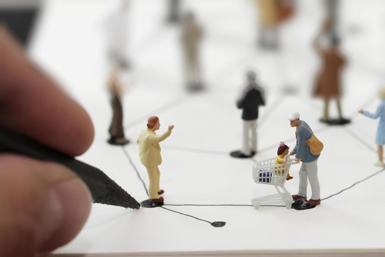 gros plan de personnes miniatures avec diagramme de réseau social sur un ordinateur portable ouvert sur un bureau en bois comme concept de médias sociaux photo