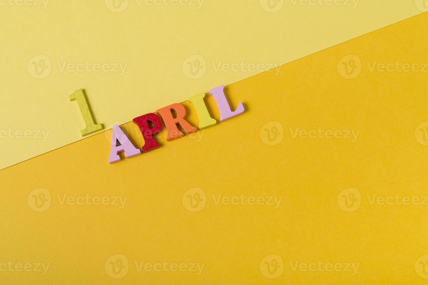 lettres en bois le premier avril sur fond jaune. le concept des vacances, photo
