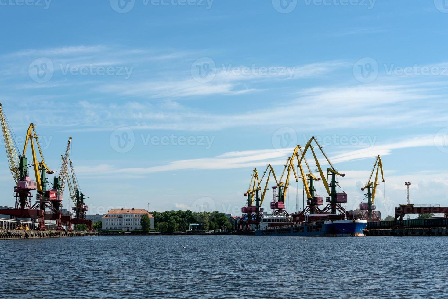 de nombreuses grues de chargement de grande taille se dressent sur les rives de la rivière venta. ventspils, lettonie, mer baltique. photo