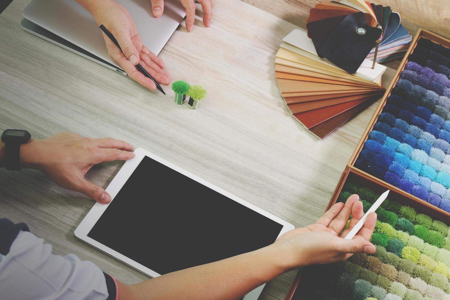 vue de dessus de deux collègues designers d'intérieur discutant des données avec une tablette numérique et un nouvel ordinateur portable moderne avec un échantillon de matériel sur un bureau en bois comme concept photo