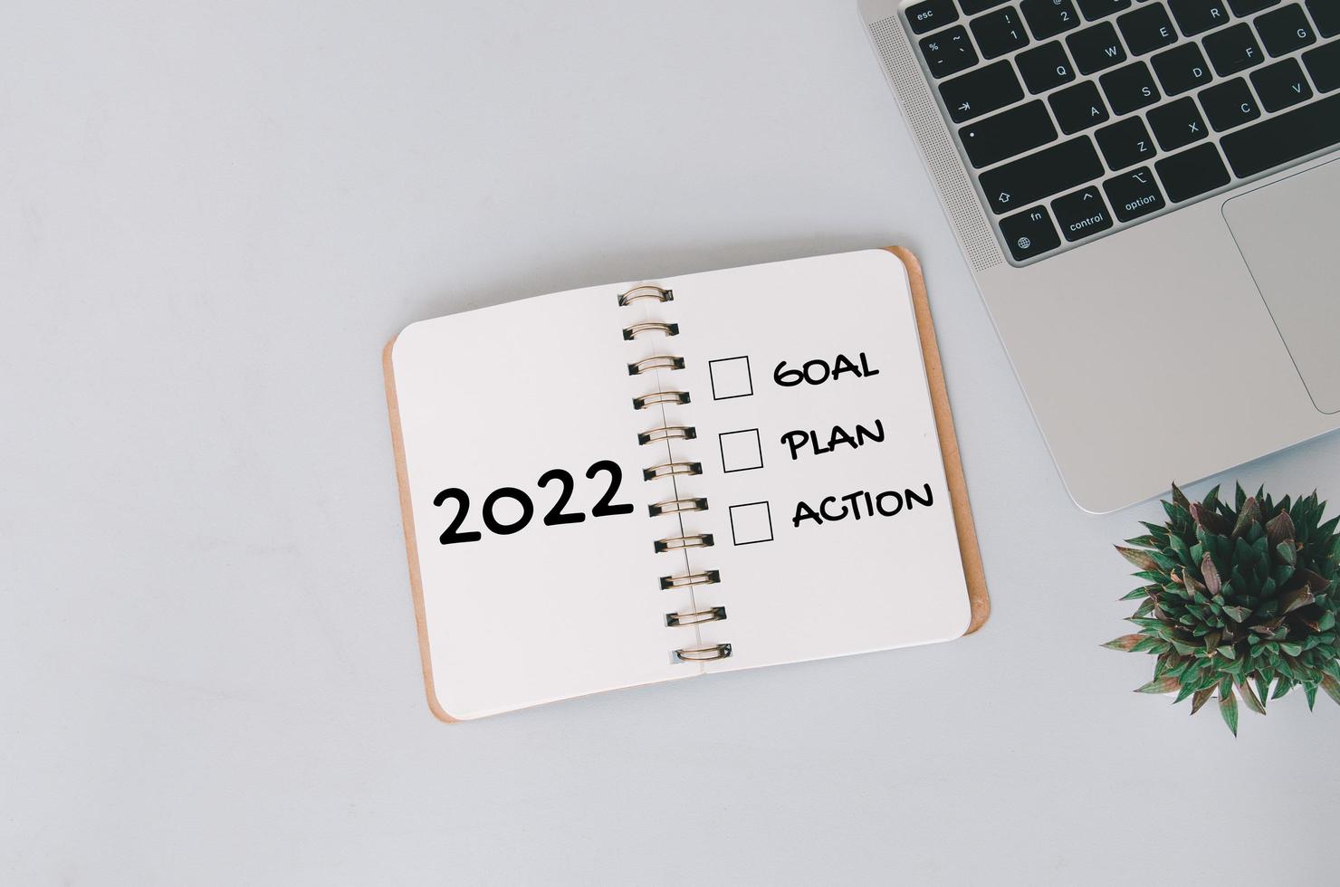 Objectif, plan, concepts d'action du nouvel an 2022 avec texte sur bloc-notes et ordinateur portable en arrière-plan. photo