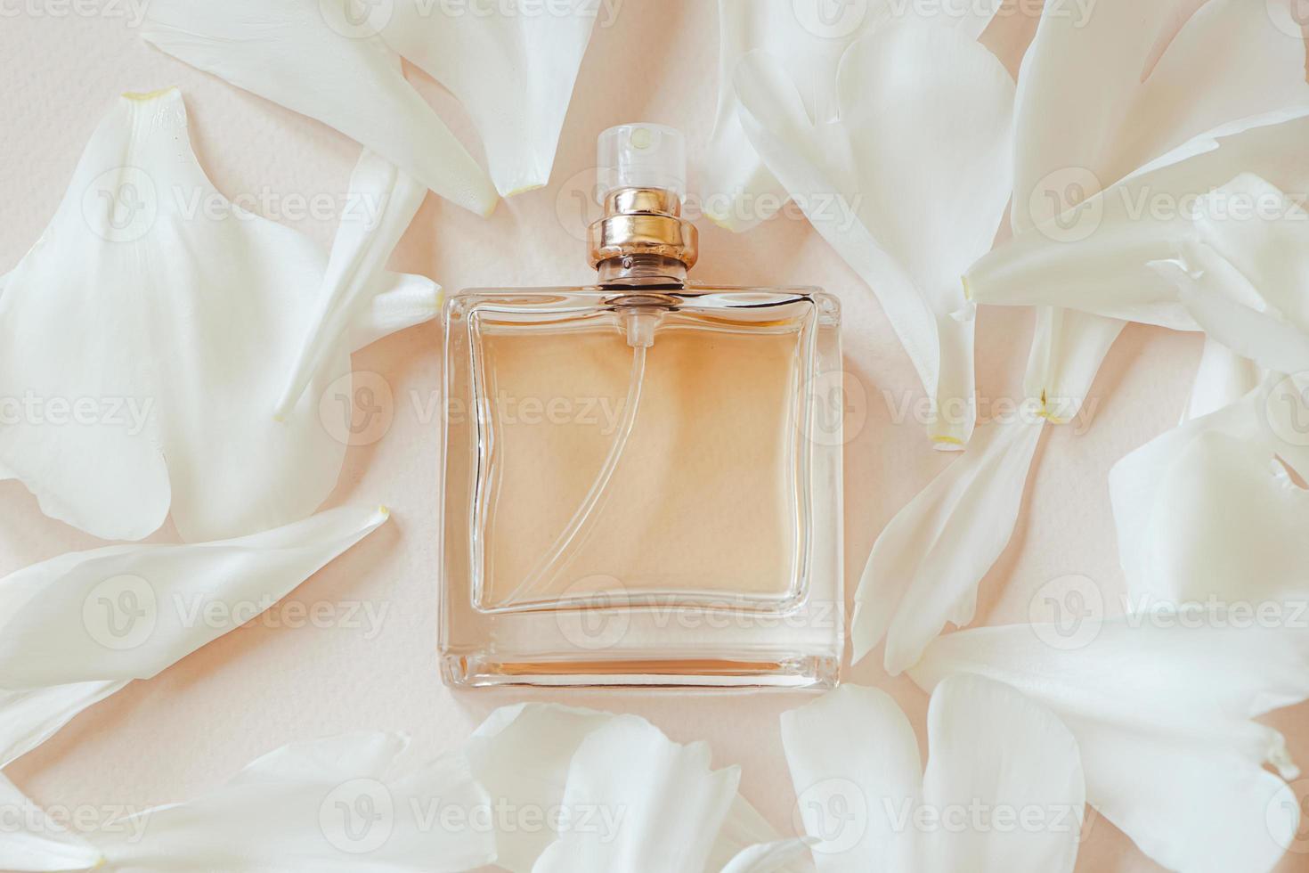 flacon de parfum et pétales de fleurs sur fond beige pastel. photo