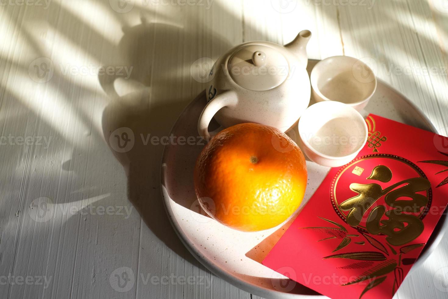 concept de festival du nouvel an chinois. mandarines, enveloppes rouges, lingots d'or et théière à fond blanc. caractère chinois fu qui signifie chance photo