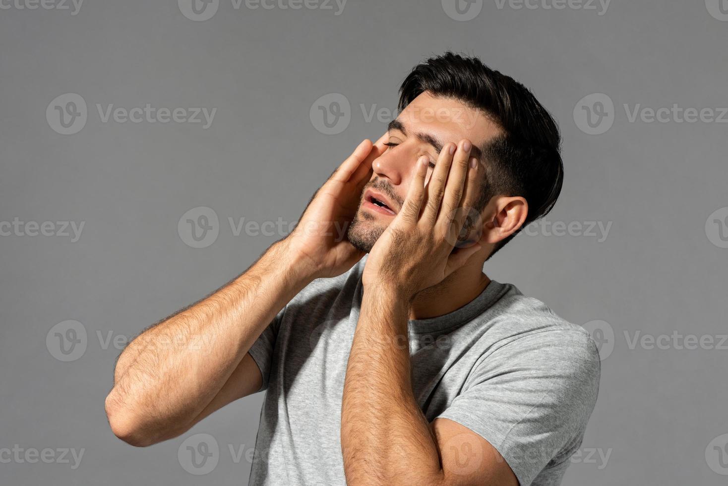Fatigué jeune homme de race blanche se sentant mal à la tête, tourné en studio sur fond gris isolé photo