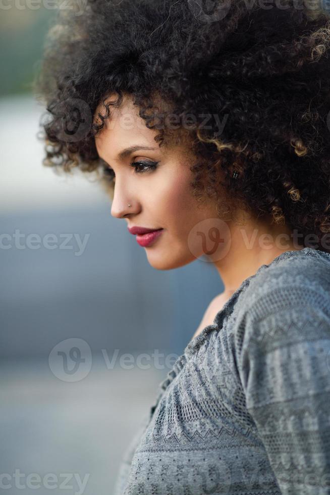 jeune femme noire avec une coiffure afro souriante en arrière-plan urbain photo