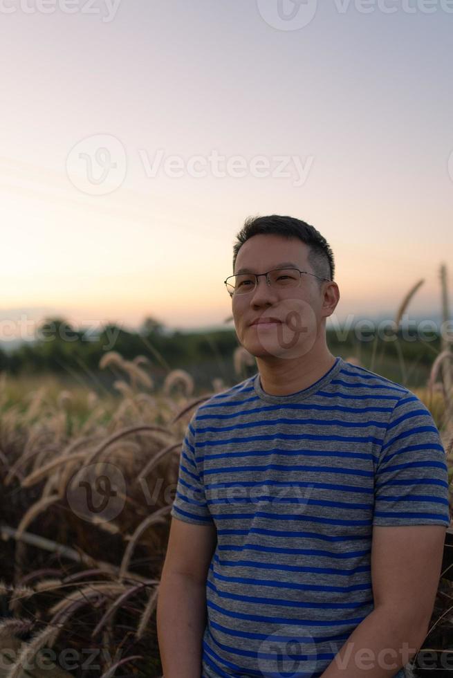 portrait d'homme debout dans un champ d'herbe au coucher du soleil photo