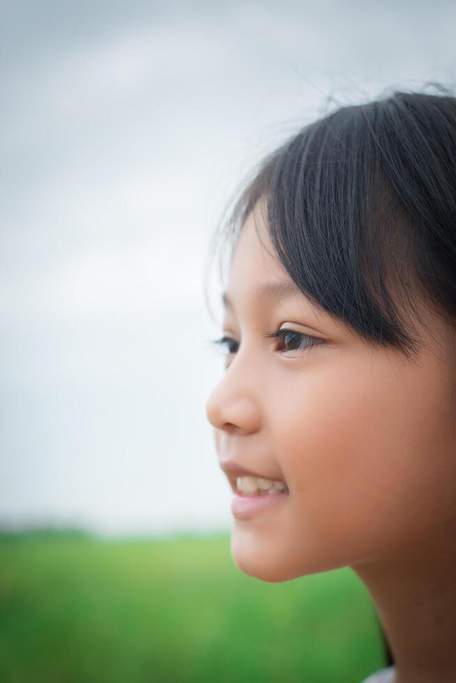 gros plan d'une douce petite fille à l'extérieur avec un sourire dans le champ d'été. photo