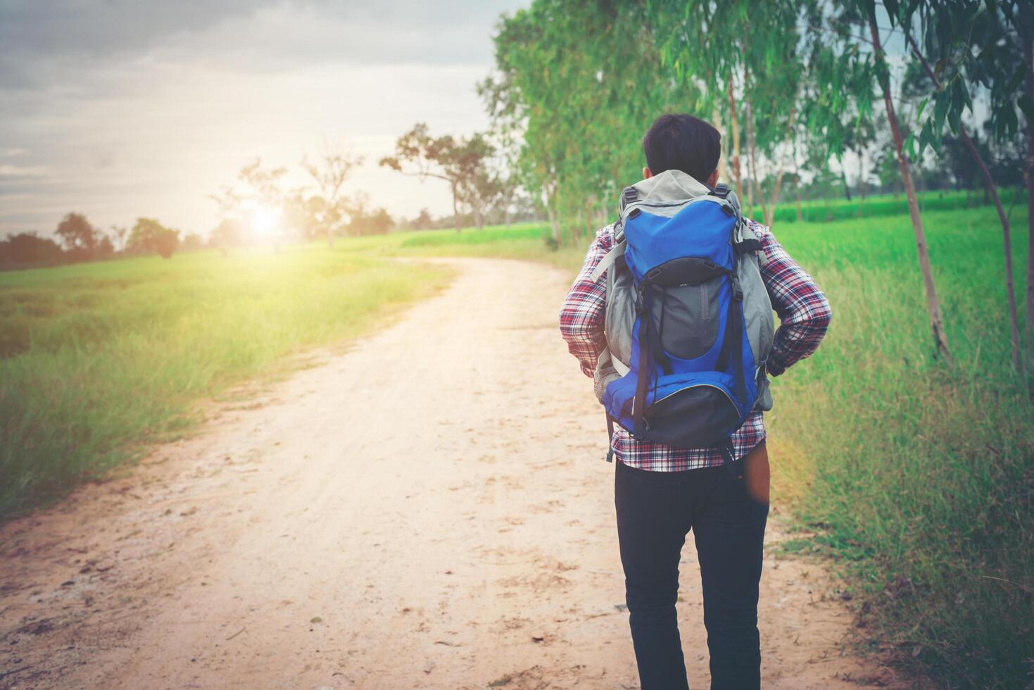 gros plan jeune homme hipster avec sac à dos sur son épaule marchant dans la campagne. photo