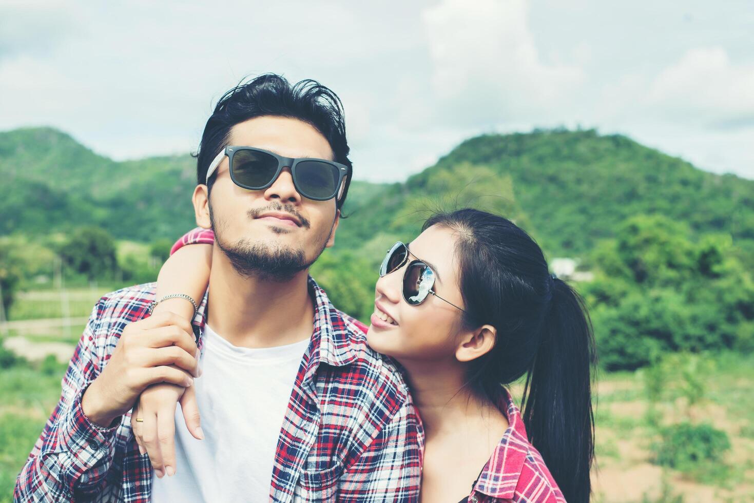 portrait en gros plan d'un couple hipster heureux amoureux portant des lunettes câlins et s'amusant avec le fond de montagne nature. photo