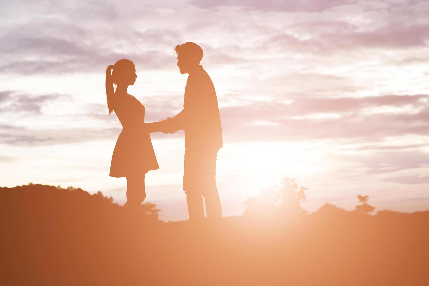silhouette de jeune couple main dans la main avec fond de coucher de soleil de montagne. photo