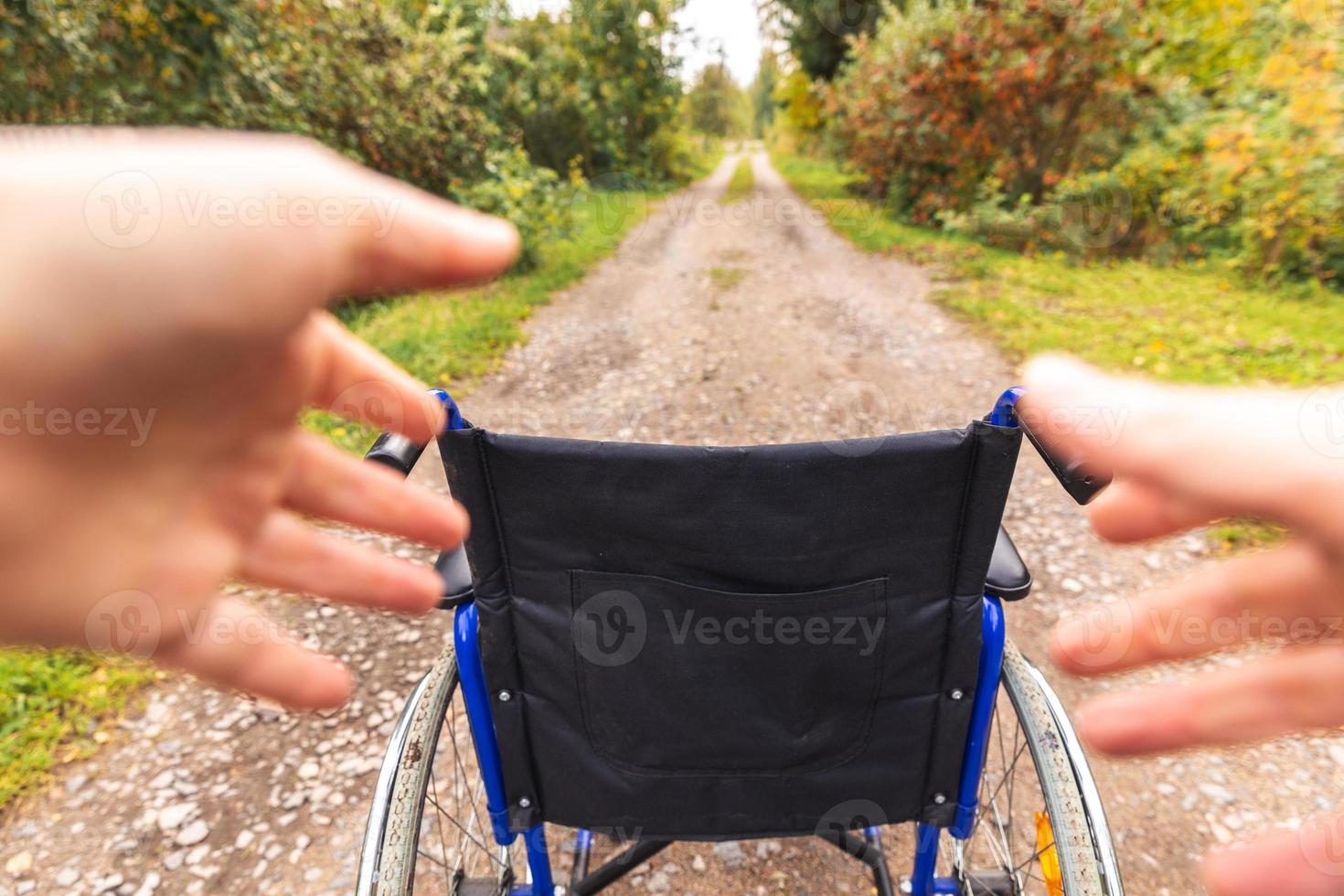 mains tenant un fauteuil roulant vide dans le parc de l'hôpital en attente de services aux patients. fauteuil roulant pour personne handicapée garé à l'extérieur. accessible pour personne handicapée. concept médical de soins de santé. photo