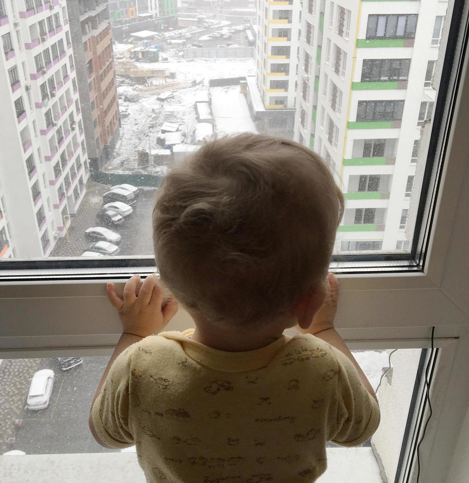 beau petit garçon avec un visage d'enfant posant un photographe près de la fenêtre photo