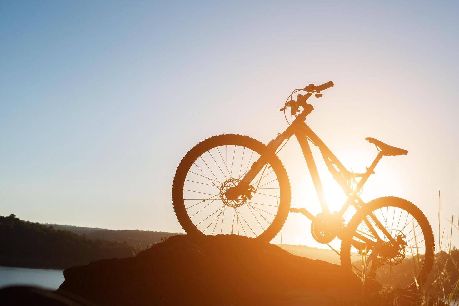 VTT silhouette sur le rocher au coucher du soleil du ciel photo