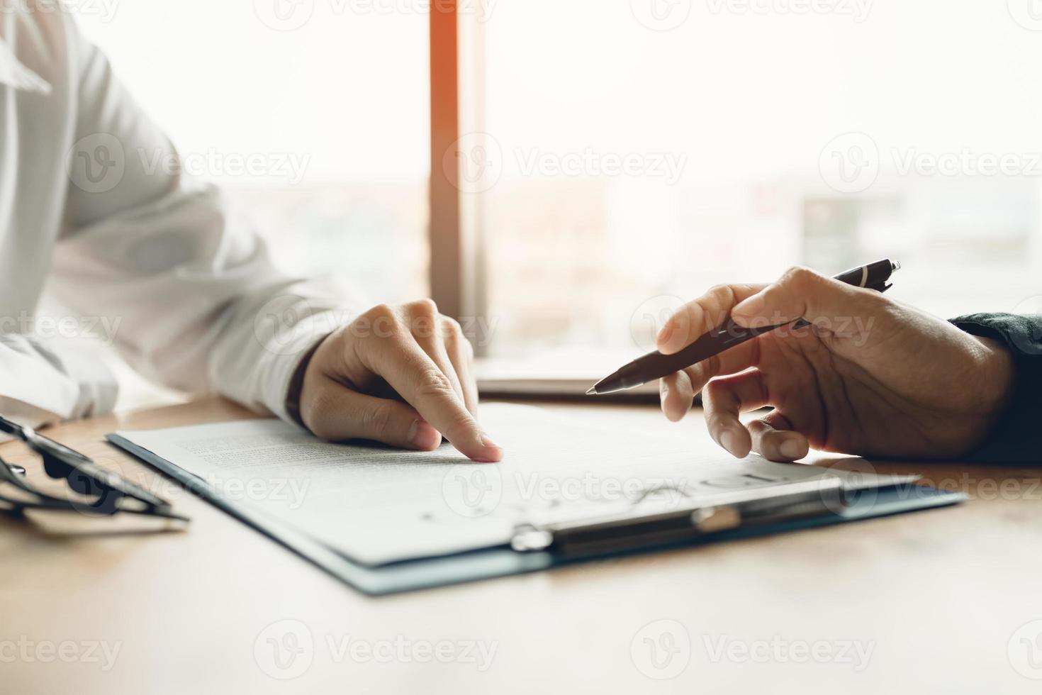 conseiller d'affaires homme financier pointant sur le papier du contrat vers le contrat de lecture du client. photo