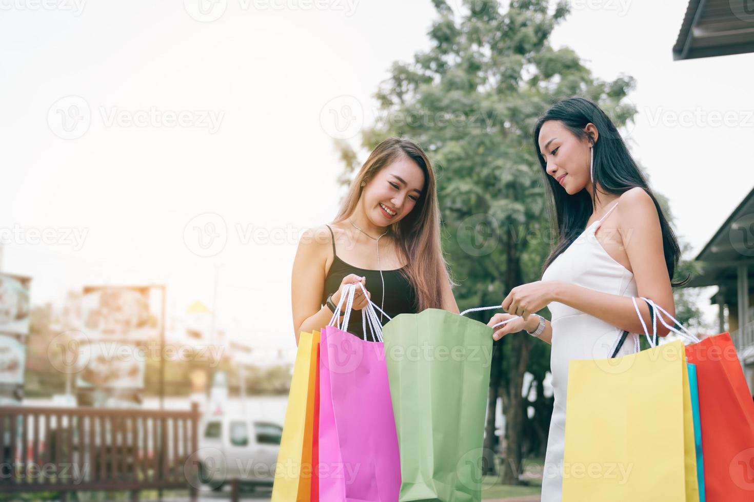 belles amies asiatiques debout et regardant dans un sac en papier au centre commercial extérieur du centre commercial de la ville. photo