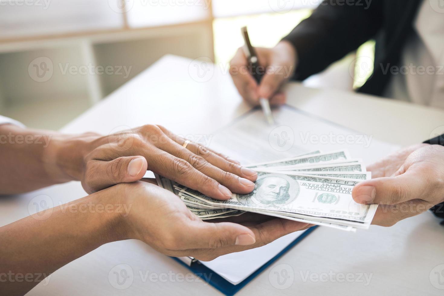 de l'argent entre les mains d'hommes d'affaires qui se soumettent à des entrepreneurs pour forcer la signature de documents contractuels sur le concept de corruption. photo