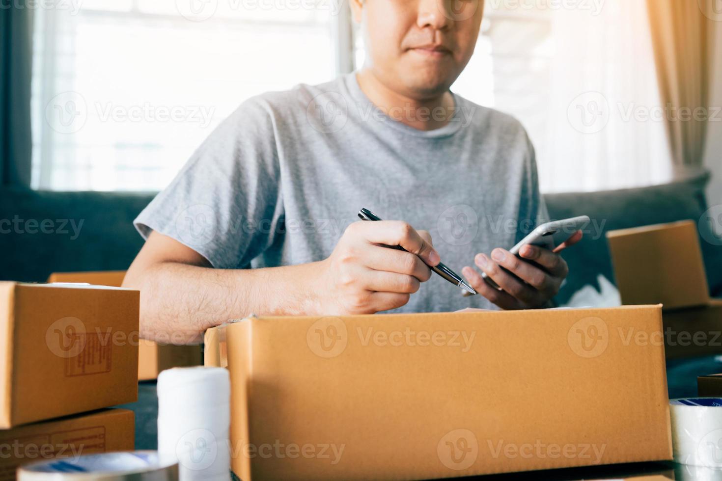 jeune homme asiatique propriétaire d'entreprise mains écrivant l'adresse sur une boîte en carton sur le lieu de travail ou au bureau à domicile. photo