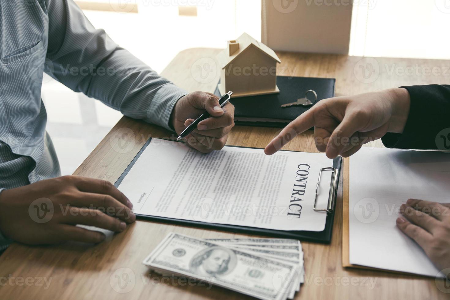 les courtiers d'assurance pointent vers la signature du contrat d'assurance et expliquent aux clients au bureau. photo