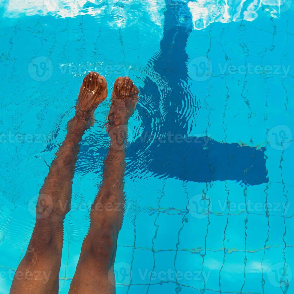 les jambes de l'homme afro-américain adulte sous l'eau dans la piscine photo