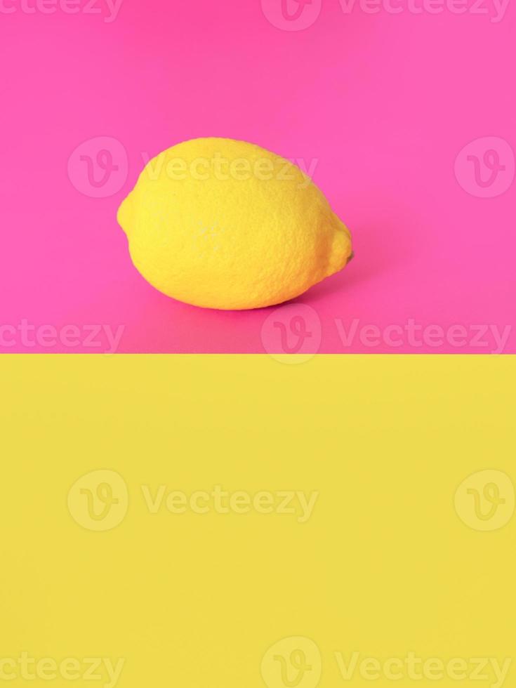 citron jaune élégant sur fond rose et jaune. agrumes, été, concept de fruits photo