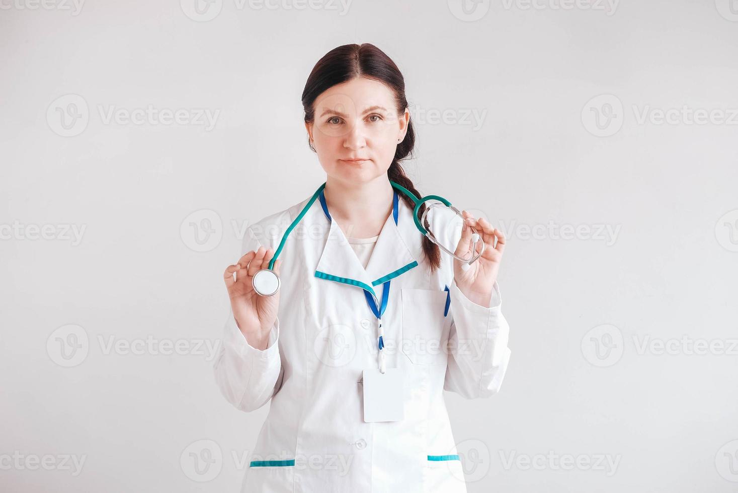 femme médecin avec un stéthoscope dans ses mains sur un fond blanc. copie, espace vide pour le texte photo