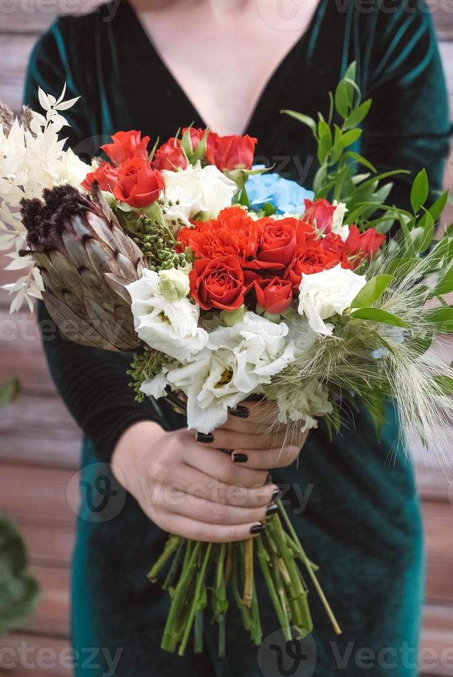 belle fille en robe verte tenant un bouquet de fleurs et de verdure sur un fond en bois. copie, espace vide pour le texte photo