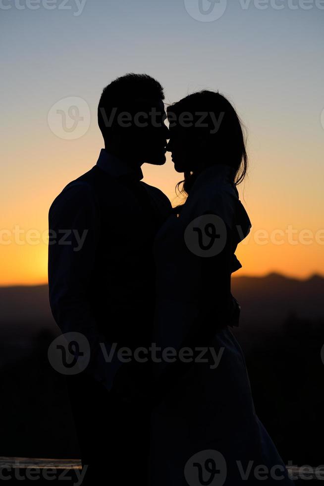silhouette de la mariée et du marié sur fond de coucher de soleil photo