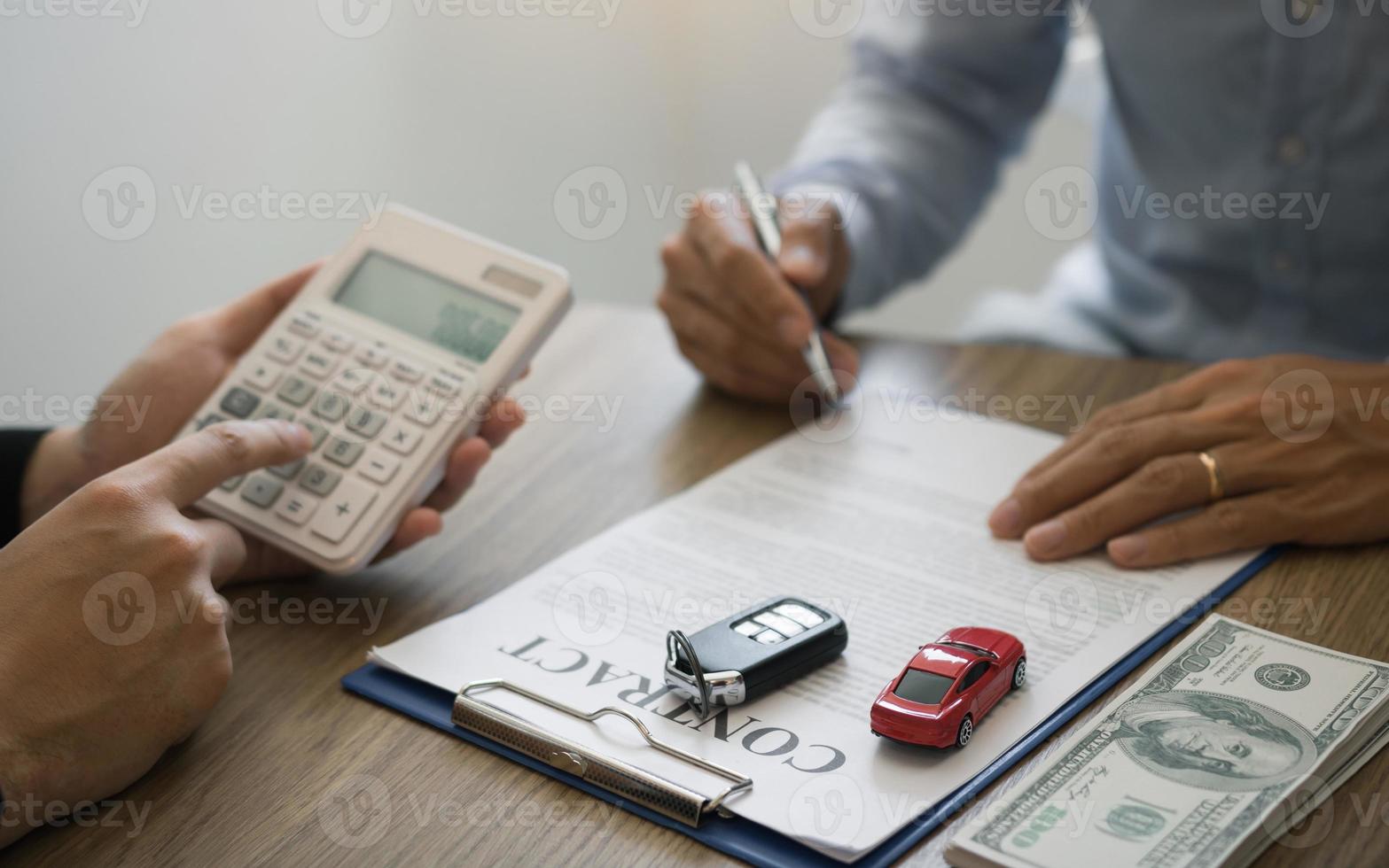 le directeur financier de la salle d'exposition automobile calcule le coût de la réservation d'une nouvelle voiture pour le client lors de la signature d'un contrat d'achat de voiture. photo