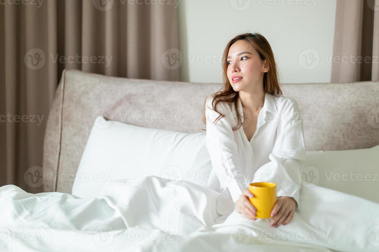 portrait belle femme se réveiller et tenant une tasse de café ou une tasse sur le lit photo