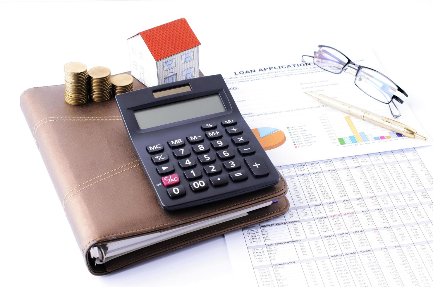 concept de prêts hypothécaires avec calculatrice et pile de pièces d'argent et papier de maison sur le tableau de rapport de document de livre de notes photo