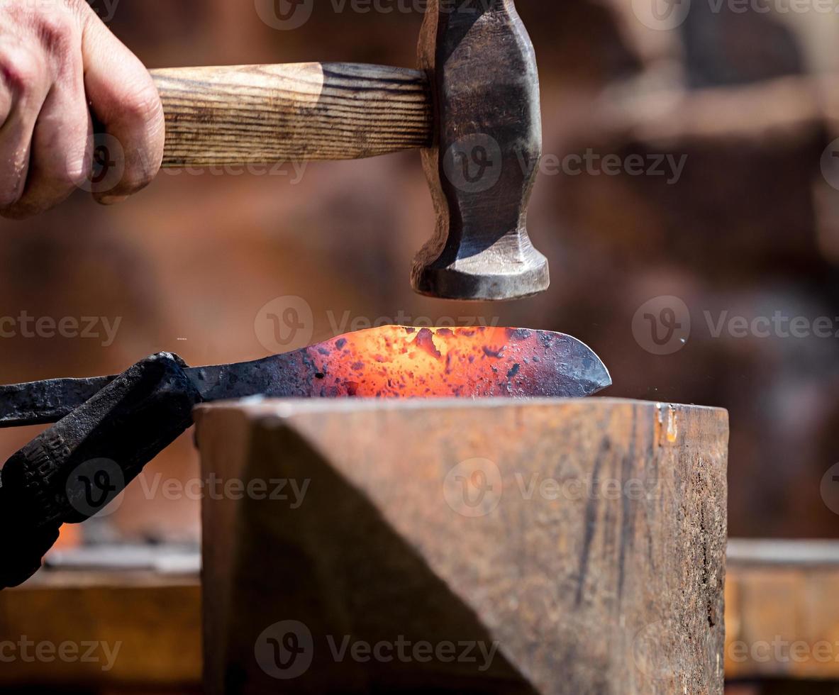 l'authentique forgeron forge le métal sur l'enclume. traditions médiévales photo