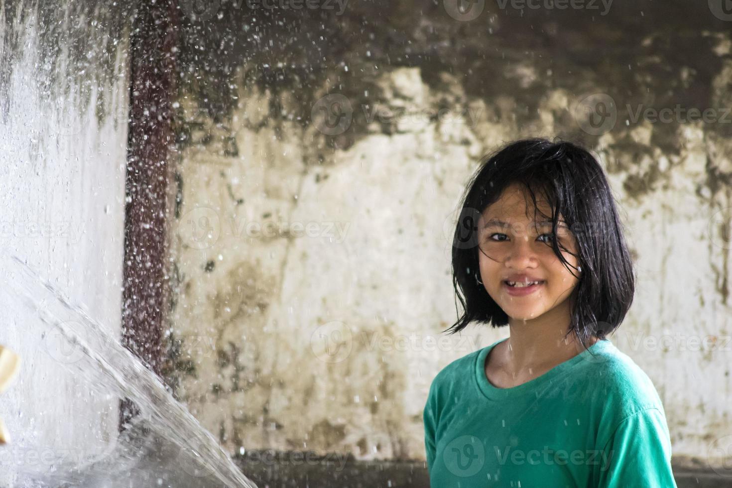 une petite fille jouant de l'eau éclaboussant avec un tuyau. photo