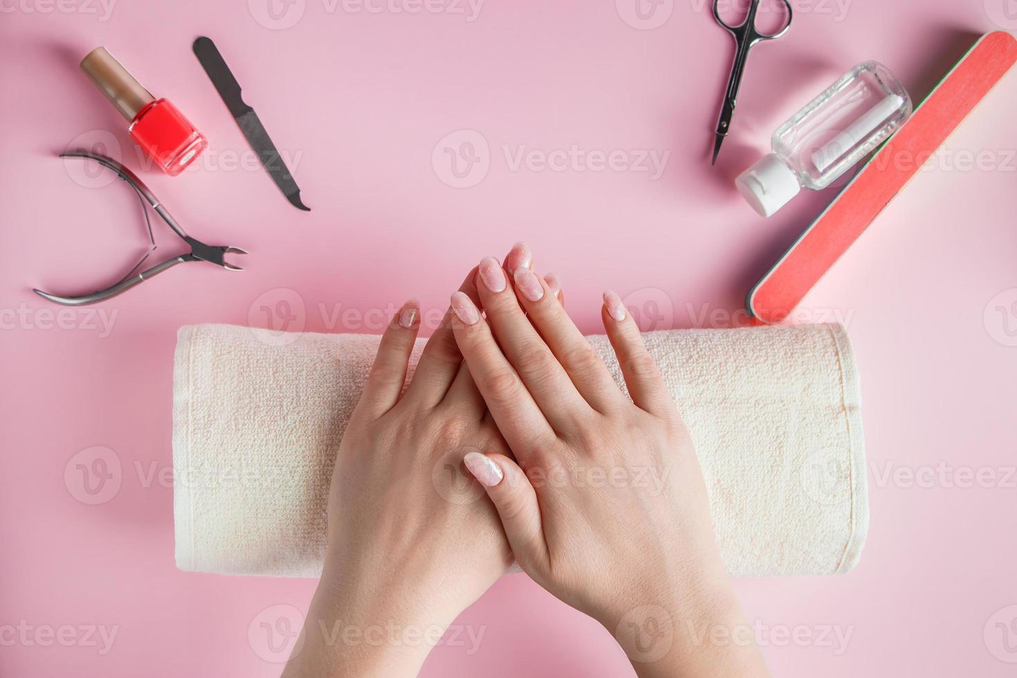 procédure de spa pour le soin des ongles dans un salon de beauté. mains féminines et outils de manucure sur fond rose. photo