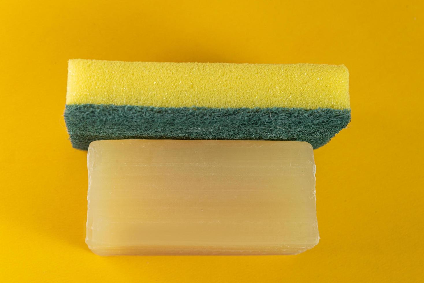 éponge de cuisine et barre de savon sur fond jaune photo