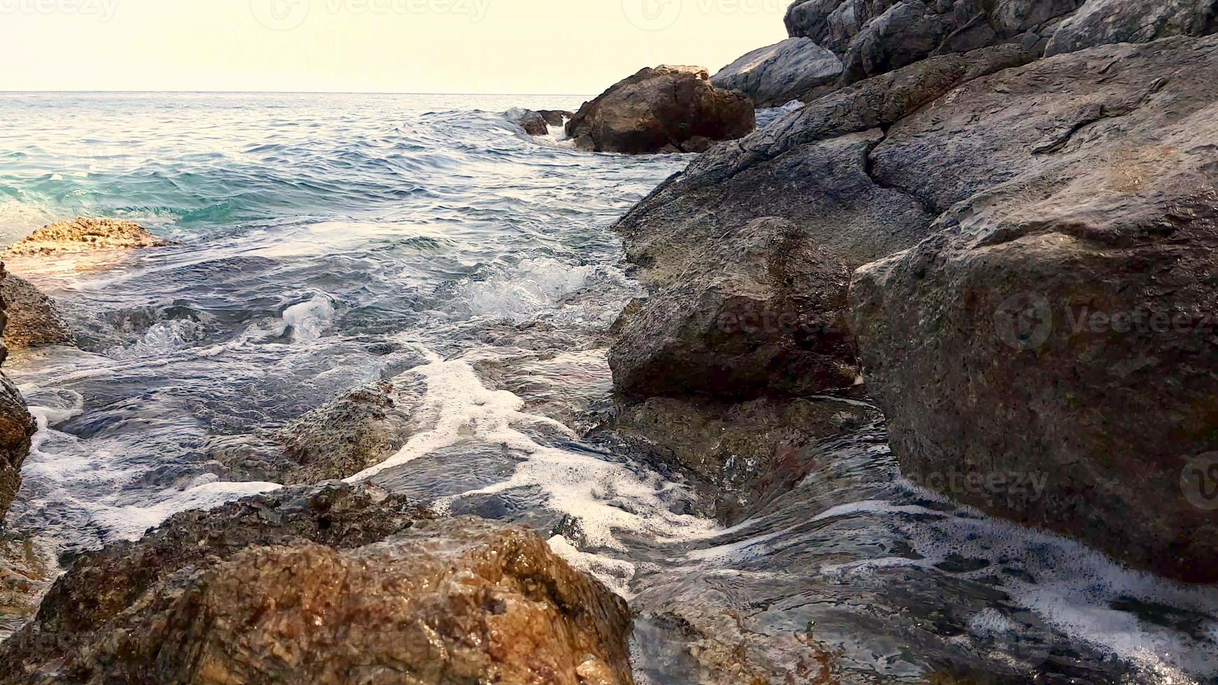 petites vagues éclaboussant sur les rochers au coucher du soleil. photo