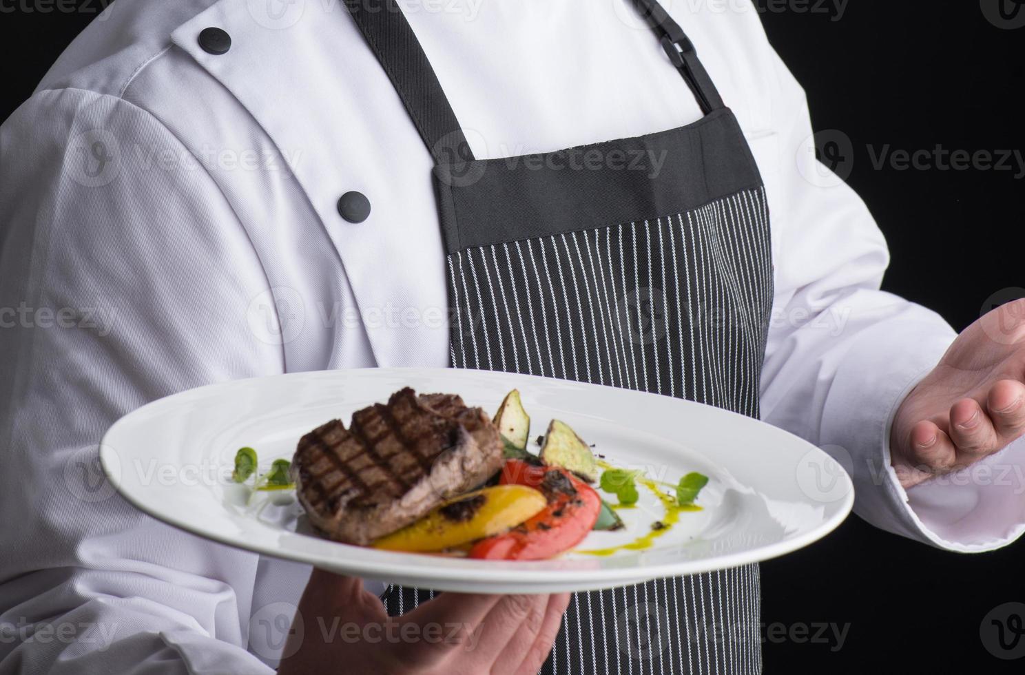 le chef en uniforme sert un plat dans une assiette photo