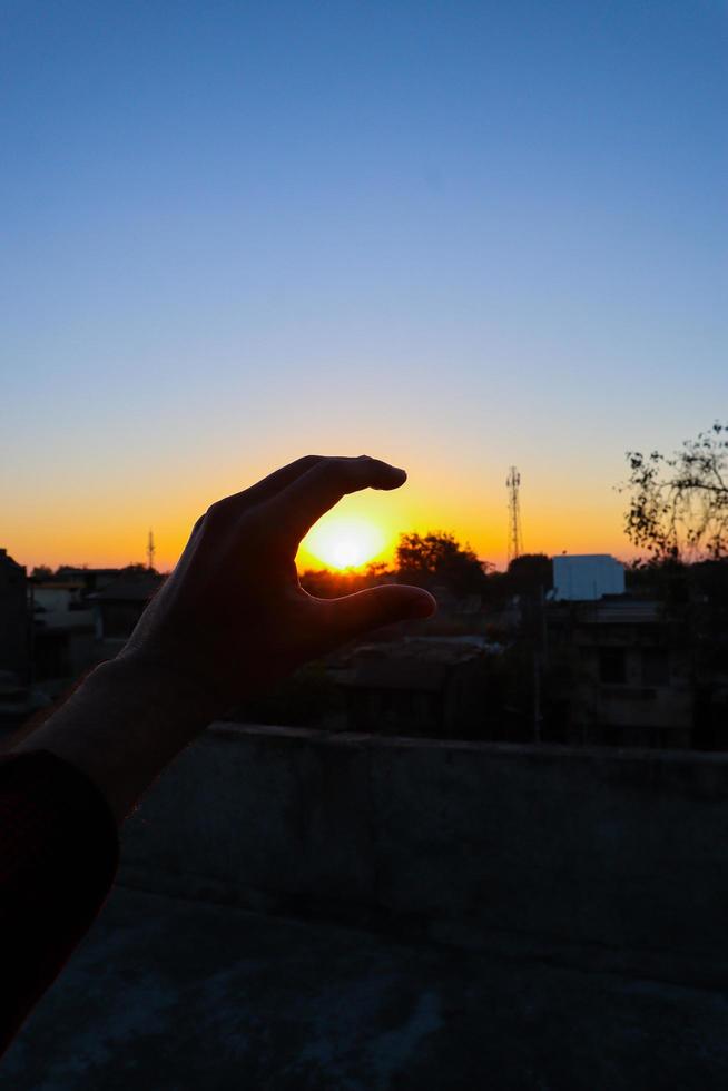 vue du coucher ou du lever du soleil derrière le signe de la main. photo