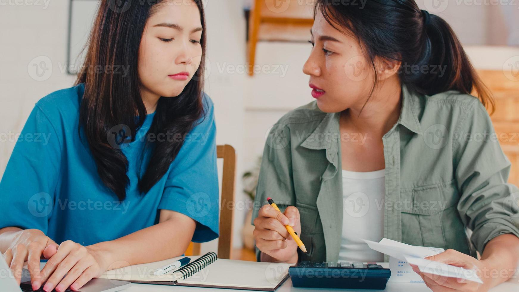 couple de femmes lgbtq lesbiennes asiatiques d'affaires compte à la maison, jeune fille asiatique sérieuse, stress lors de l'utilisation du budget d'enregistrement de la calculatrice, impôt, document financier sur ordinateur portable travaillant dans le concept de cuisine. photo