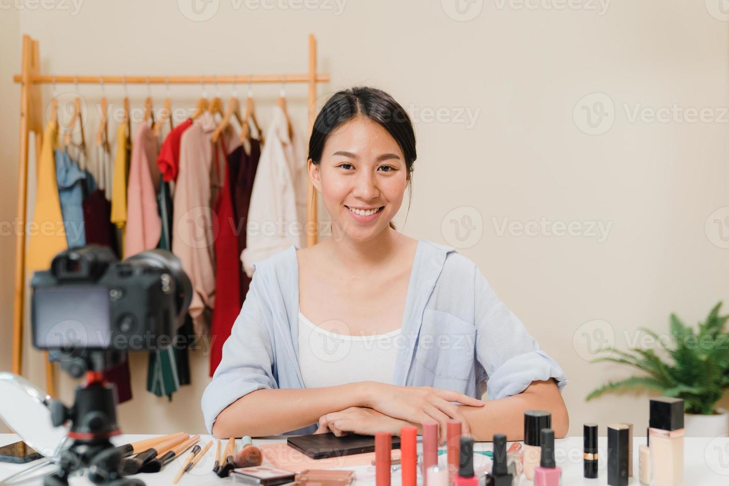 une blogueuse beauté présente des cosmétiques de beauté assis devant la caméra pour enregistrer une vidéo. belle femme asiatique utiliser des cosmétiques examen maquillage tutoriel diffuser une vidéo en direct sur le réseau social par internet. photo