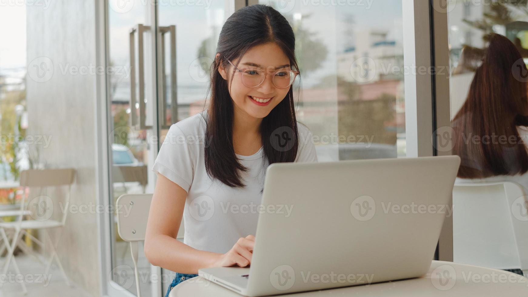 femmes asiatiques indépendantes travaillant sur ordinateur portable au café. jeune fille d'affaires d'asie utilisant un ordinateur pour le commerce, envoyer des e-mails, travail numérique sur internet sur table au café en plein air dans le concept de soirée. photo