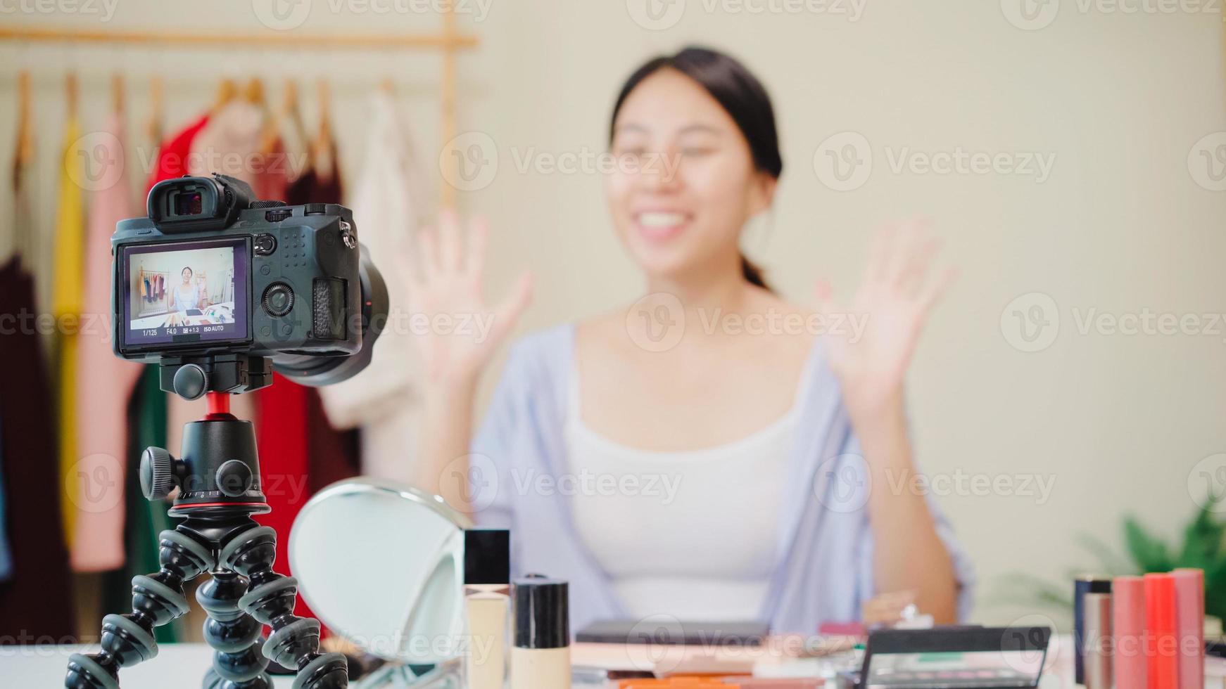 une blogueuse beauté présente des cosmétiques de beauté assis devant la caméra pour enregistrer une vidéo. belle femme asiatique utiliser des cosmétiques examen maquillage tutoriel diffuser une vidéo en direct sur le réseau social par internet. photo