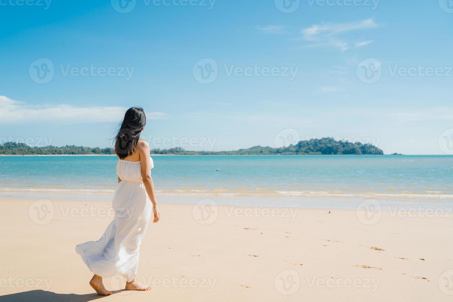 belle jeune femme asiatique heureuse se détendre en marchant sur la plage près de la mer. les femmes de style de vie voyagent sur le concept de plage. photo