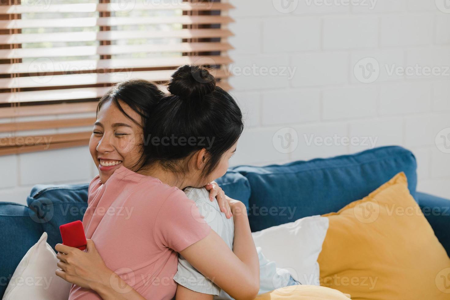 couple de femmes lgbtq lesbiennes asiatiques propose à la maison, jeune amante asiatique femme heureuse souriante avoir du temps romantique tout en proposant et mariage surprise porter une bague de mariage dans le salon à la maison concept. photo