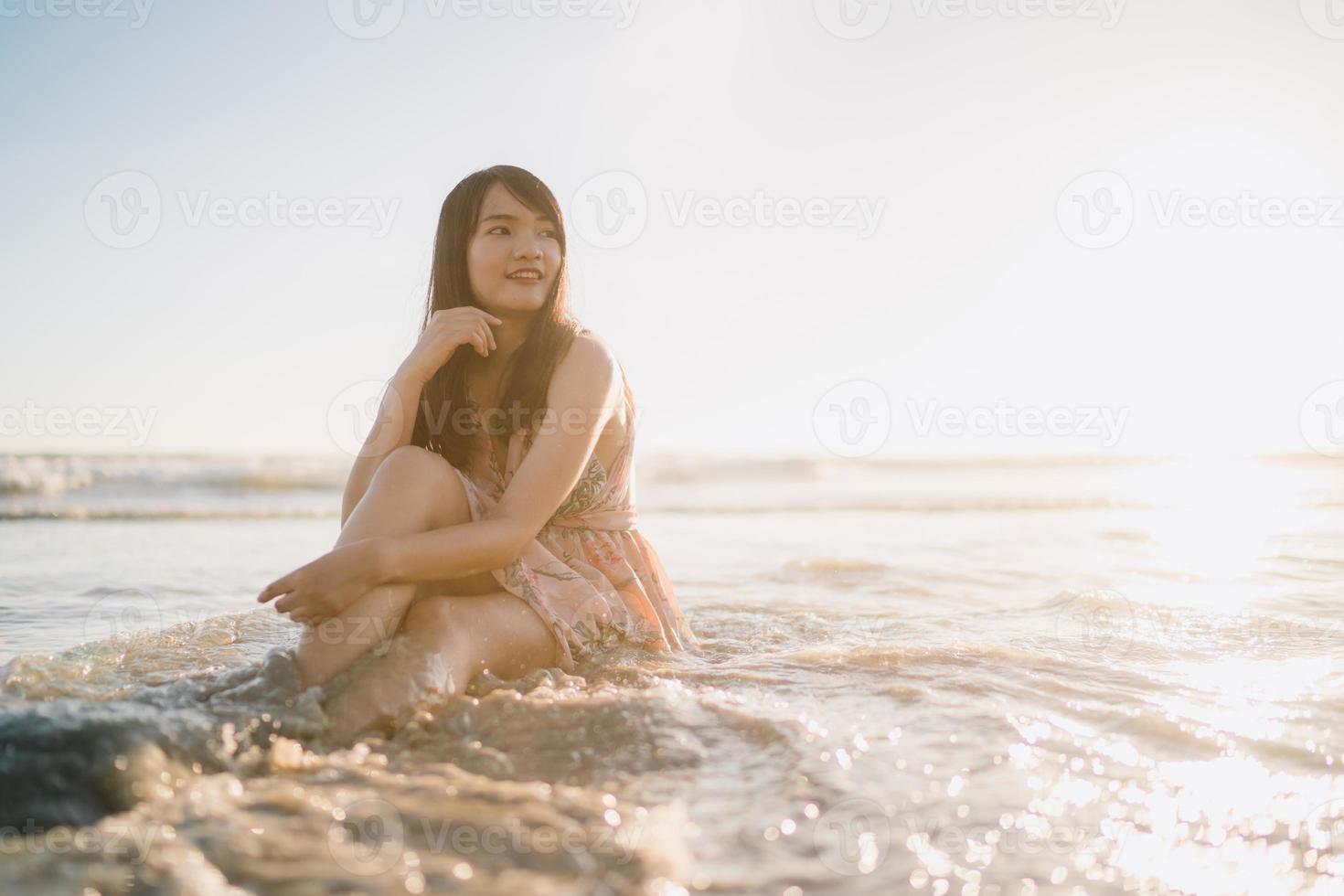 jeune femme asiatique se sentant heureuse sur la plage, belle femme heureuse se détendre souriant amusant sur la plage près de la mer au coucher du soleil le soir. les femmes de style de vie voyagent sur le concept de plage. photo