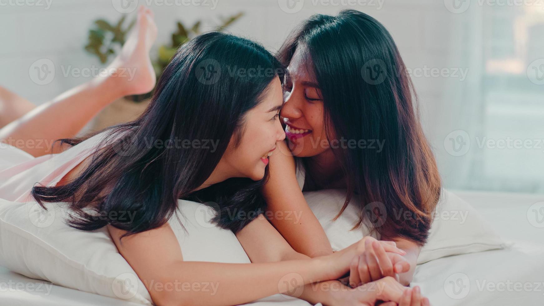 couple de femmes lgbtq lesbiennes asiatiques parlant sur le lit à la maison. jeune amant d'asie femme heureuse se détendre se reposer ensemble après le réveil en position couchée sur le lit dans la chambre à la maison dans le concept du matin. photo