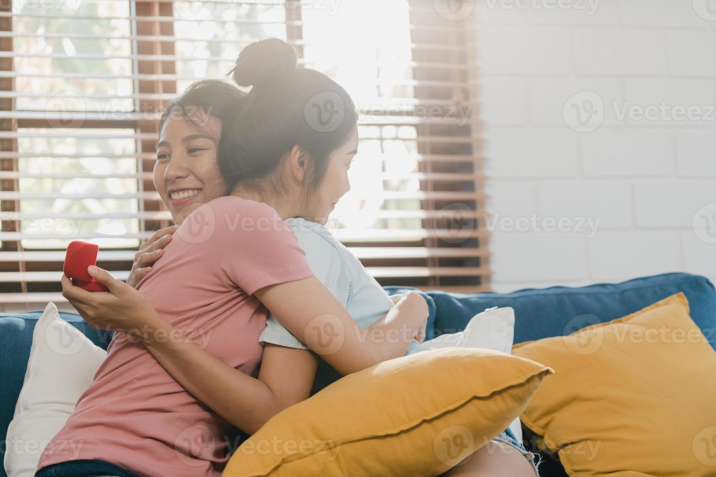 couple de femmes lgbtq lesbiennes asiatiques propose à la maison, jeune amante asiatique femme heureuse souriante avoir du temps romantique tout en proposant et mariage surprise porter une bague de mariage dans le salon à la maison concept. photo