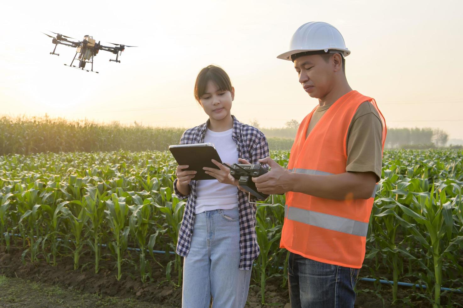 un ingénieur masculin fournit une consultation et donne des instructions à un agriculteur intelligent avec un drone pulvérisant des engrais et des pesticides sur les terres agricoles, des innovations de haute technologie et une agriculture intelligente photo