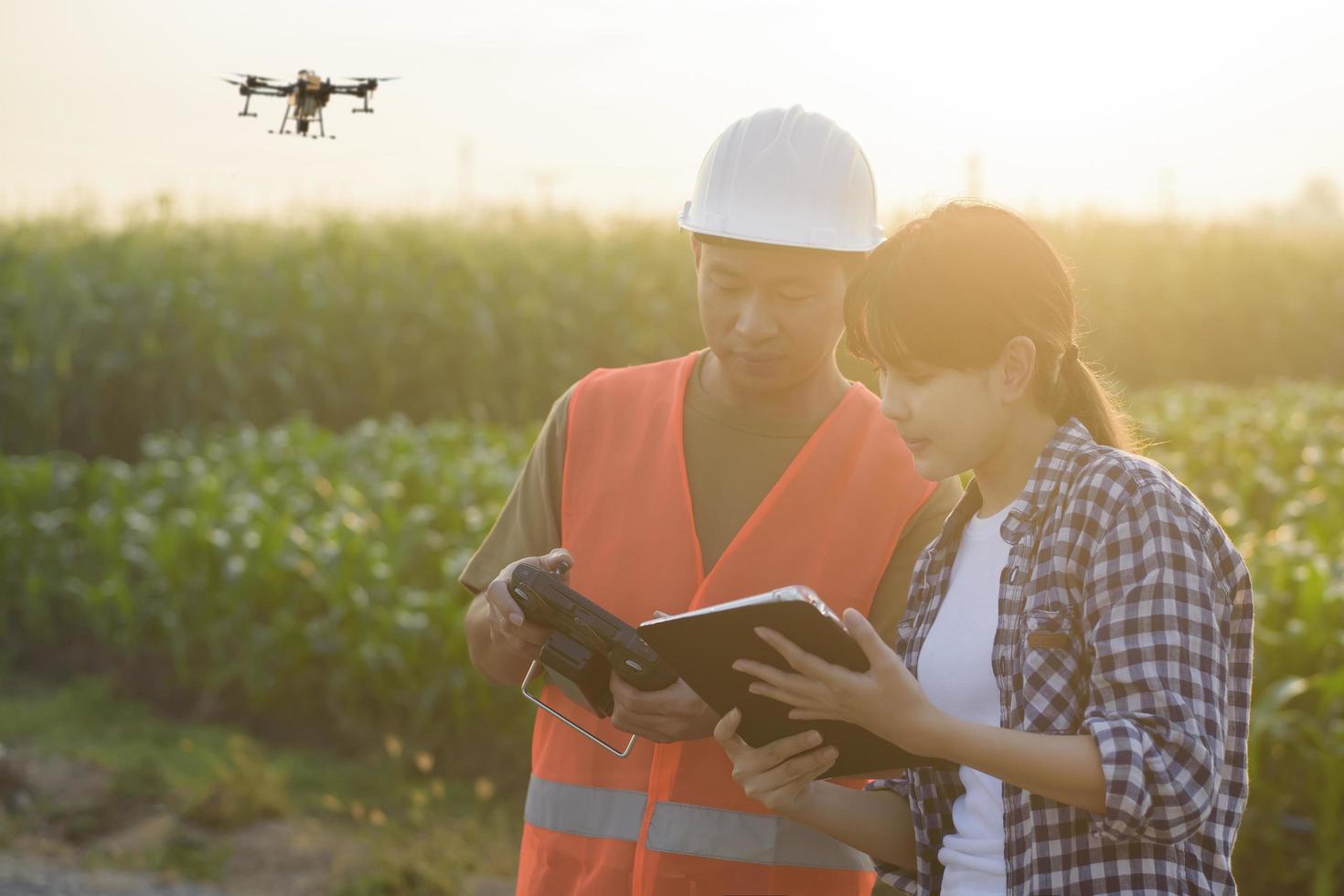 un ingénieur masculin fournit une consultation et donne des instructions à un agriculteur intelligent avec un drone pulvérisant des engrais et des pesticides sur les terres agricoles, des innovations de haute technologie et une agriculture intelligente photo