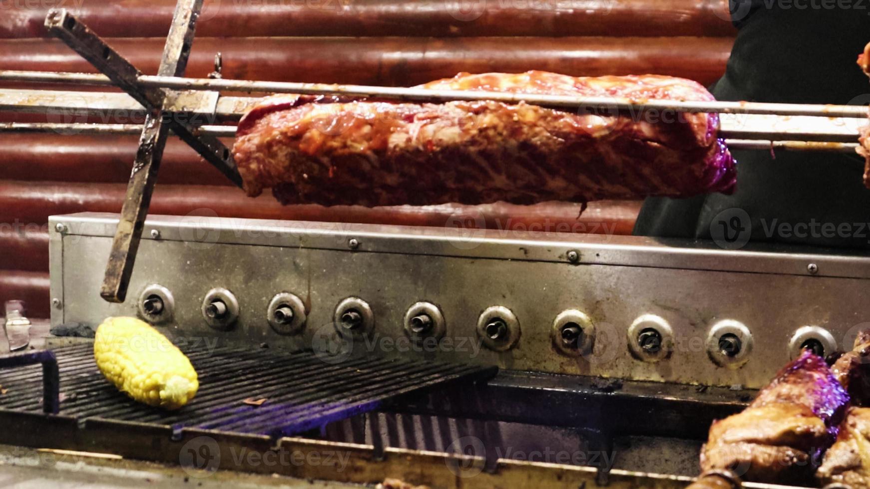 la viande des côtes tourne sur le gril du restaurant. un cuisinier en gants prépare une nouvelle portion sur le barbecue. nourriture grillée. le bœuf ou le porc est cuit jusqu'à ce qu'il soit croustillant. un plat populaire photo